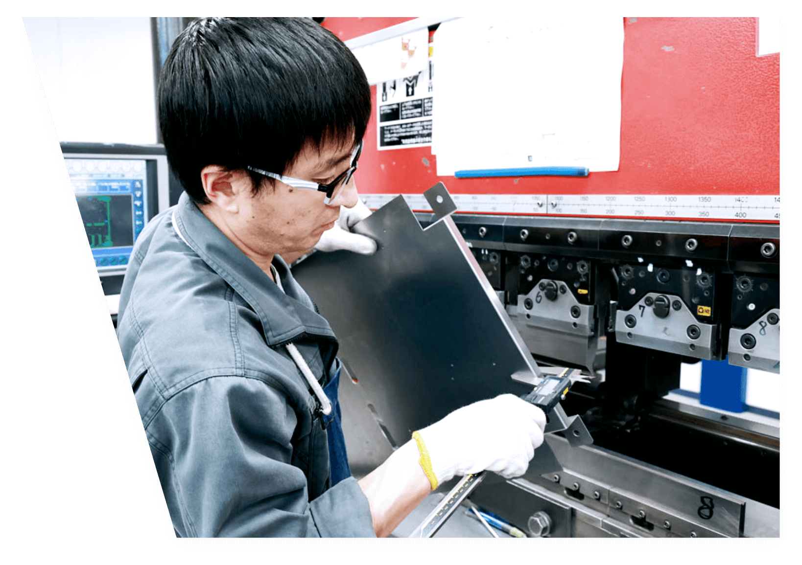 作業者が金属板を機械にセットし、ノギスで寸法を測定しながら精密に加工している様子が映っている。