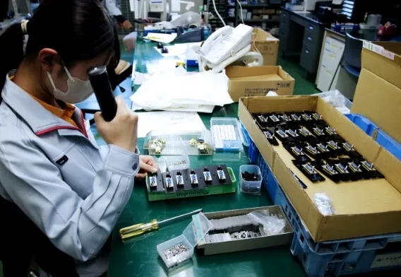 製造現場で部品の検査と加工が行われており、精密な作業風景が切り取られている