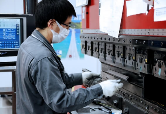 製造現場で部品の検査と加工が行われており、精密な作業風景が切り取られている